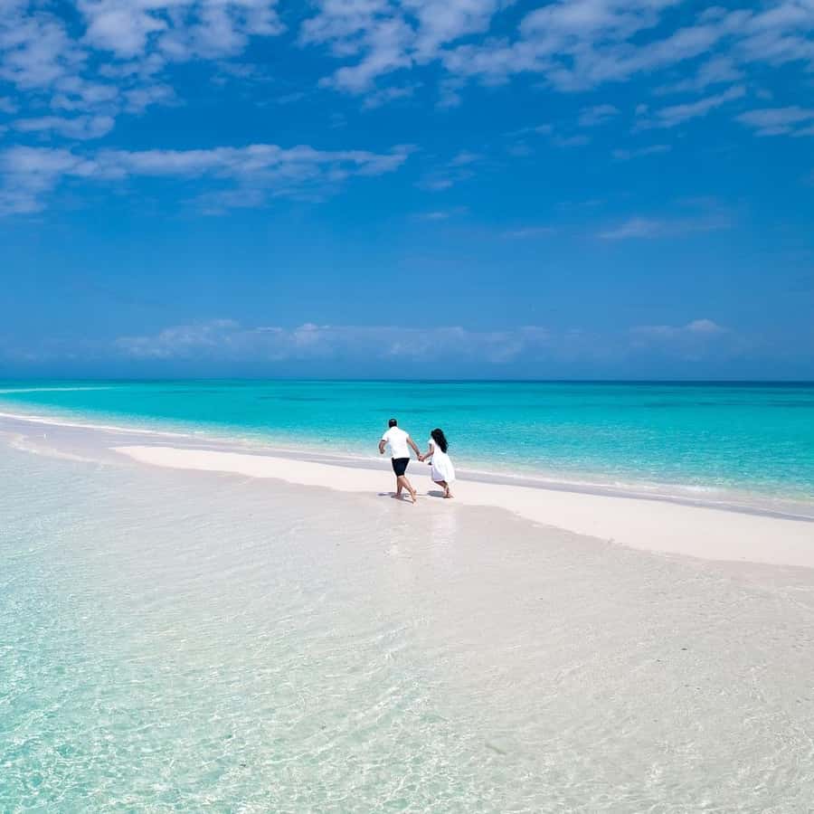 A couple walking bare foot in private sandbank