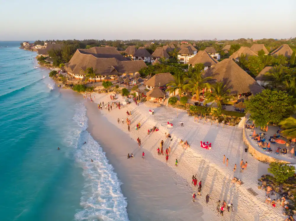 "couple walking along white sand beach at Kendwa during Golden hour"